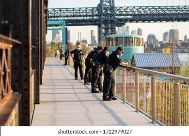 New York, USA - May 5 2020: Police Officers in Groups in Domino Park Overseeing People and Crowds For Social Distancing Wearing Uniforms and Masks Overlooking Manhattan Waterfront