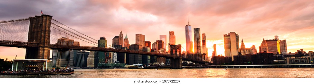  New York, USA. Aussicht auf die Manhattan-Brücke und Manhattan in New York, USA bei Sonnenuntergang. Farbiger bewölkter Himmel mit Wolkenkratzern. Hinter den Wolkenkratzern die Sonne