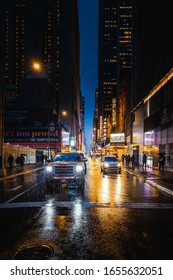 New York, New York/USA - February 6th 2020: Cars with bright headlights in a colorful street on a rainy evening