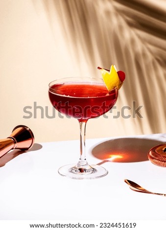 New Yorker red cocktail with whiskey, grenadine, bitter, lemon and ice garnished with lemon zest and cocktail cherry in glass. Beige background, hard light