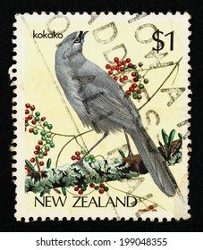 NEW ZEALAND - CIRCA 1985: Postage stamp printed in New Zealand with image of an endangered Kokako bird perched on a tree branch.