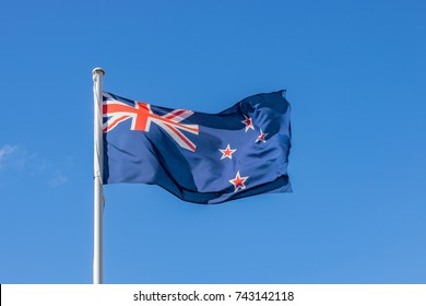 New Zealand Flag Flying High In Blue Sky On Anzac Day