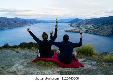 New Zealand, Wanaka Lake Travel Vacation. Happy Couple/friends Happy On The Mountain Top Hands Up With Wine Glasses, Enjoying Mountain, Lake Landscape Outdoor View. Freedom, Happiness Lifestyle