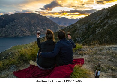 New Zealand, Wanaka Lake Travel Holidays. Happy Couple/friends Tourists On The Mountain Top Hands Up With Wine Glasses, Enjoying Mountain, Lake Landscape Outdoor View. Freedom, Happiness Lifestyle