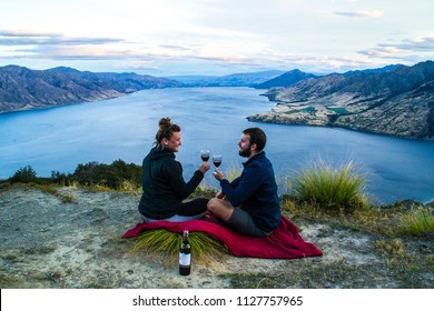 New Zealand, Wanaka Lake Travel Vacation. Happy Couple/friends Happy On The Mountain Top Hands Up With Wine Glasses, Enjoying Mountain, Lake Landscape Outdoor View. Freedom, Happiness Lifestyle