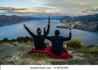 New Zealand, Wanaka Lake Travel Vacation. Happy Couple/friends Happy On The Mountain Top Hands Up With Wine Glasses, Enjoying Mountain, Lake Landscape Outdoor View. Freedom, Happiness Lifestyle