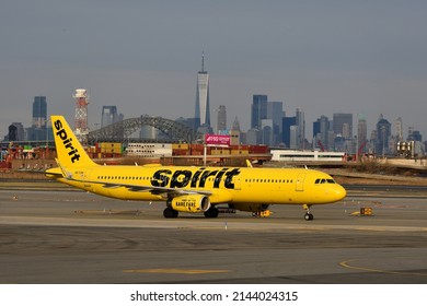 NEWARK, NJ - April 04, 2022: Spirit Airline Yellow Airbus A321 taxis on the tarmac at Newark Airport with the New York skyline in background with sun and grey skies. Tail number N672NK