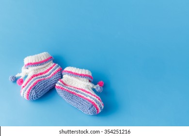 Newborn announcement. knitted baby booties on plain blue background - Powered by Shutterstock