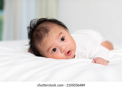 Newborn baby 3 month laying on stomach developing neck control .tummy time for strengthen baby neck and shoulder muscles.Cute infant lying crawling on white bed happiness and fun.Tummy Time Concept