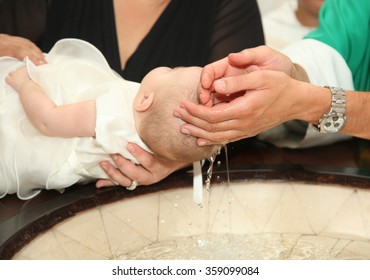 Newborn baby baptism by water with hands of priest