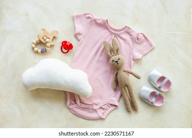 Newborn baby bodysuit with rabbit toy, flat lay, top view