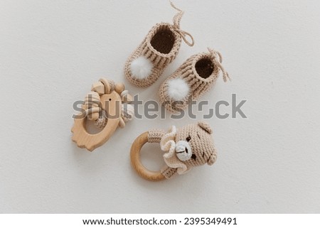 Newborn baby booties and wooden rattles on a white background. Concept of waiting for a baby to be born. Isolated image.