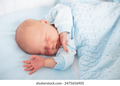 Newborn baby boy in bed. New born child sleeping under a blue knitted blanket. Children sleep. Bedding for kids. Infant napping in bed. Healthy little kid shortly after birth. Cable knit textile. - Powered by Shutterstock