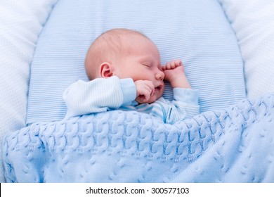 Newborn Baby Boy In Bed. New Born Child Sleeping Under A Blue Knitted Blanket. Children Sleep. Bedding For Kids. Infant Napping In Bed. Healthy Little Kid Shortly After Birth. Cable Knit Textile.