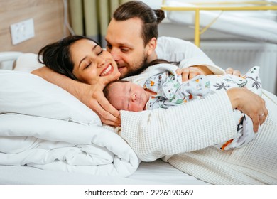 Newborn baby boy being cradled by new mother and father in birthing center. Joy and happiness emotions at faces of new parents.