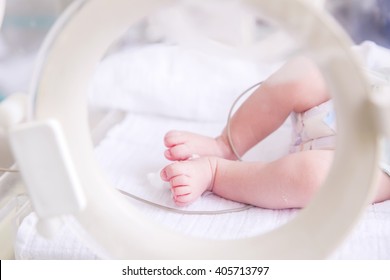 Newborn baby boy covered in vertix inside incubator