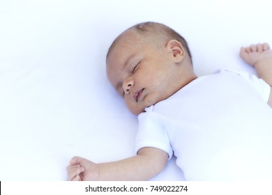 Newborn Baby Boy Sleeping On Back On A White Blanket