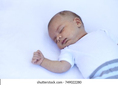 Newborn Baby Boy Sleeping On Back On A White Blanket