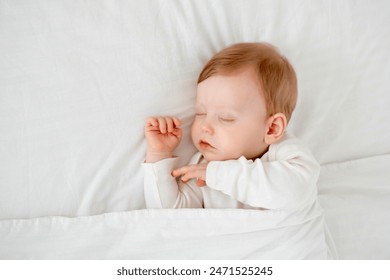 Newborn baby boy sleeping under a blanket in a white bodysuit on the bed with his hand folded under his cheek, sweet healthy baby sleep at home - Powered by Shutterstock