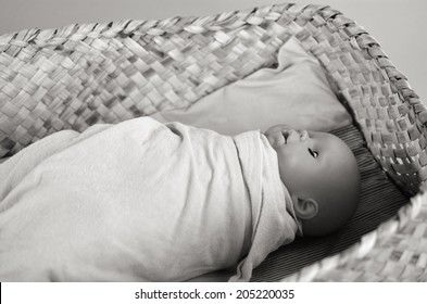 Newborn Baby Doll Sleep In A Traditional Maori Weaving Basket In Auckland, New Zealand. 