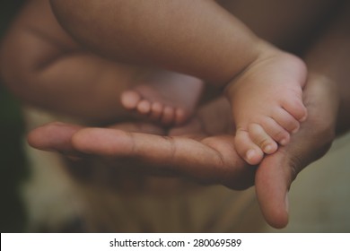 Newborn baby feet in father's hands
