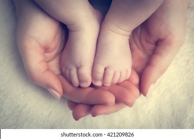 Newborn Baby Feet In Mother's Hands. Concept Of Child Care, Feeling Safe, Protect. Vintage