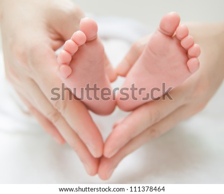 newborn baby feet on female hands, shape like a lovely heart