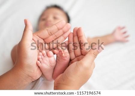 Newborn baby feet on female hands, shape like a lovely heart, Baby feet in mother hands. Mom and her child. Happy family concept