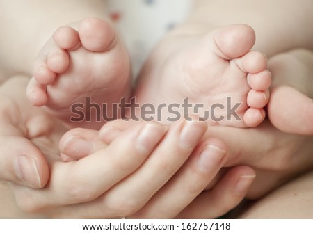 newborn baby feet on female hands 