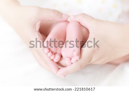 newborn baby feet on mother hands
