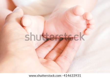 Newborn baby feet on mother hands