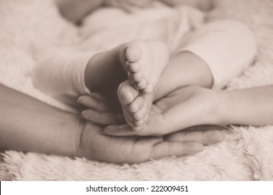 Newborn Baby Feet Parents Holding In Hands. New Born Kind And Love Symbol As Heart Sign. Vintage Colour