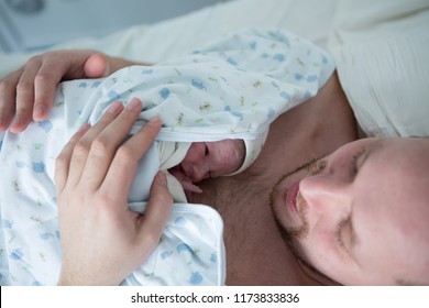 Newborn Baby First Days With His Dad. Skin To Skin. Mega Emotions Of Father, For The First Time Holding Child In His Arms. Beautiful Hands Of Daddy. In The Hospital. Birth Concept.