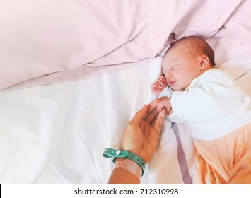 Newborn Baby First Days Of Life In Delivery Room. Infant Asleep In Hospital After Childbirth. New Born And His Mother With Name Tag Bracelets.