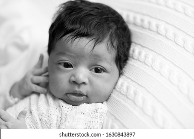 Newborn Baby Girl, 9 Days Old, Laying In A White Blanket With Her Eyes Wide Open.