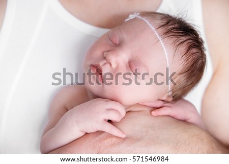 Newborn baby girl in the arms of his dad on a white background.