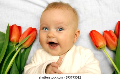 Newborn Baby Girl Boy Laughing And Showing Thumb Up Among Red Tulips