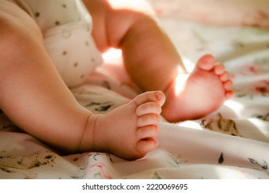 Newborn Baby Girl In The Cradle. Toddlers Legs In The Bed. Two Month Caucasian Infant In The Nappy. Small Baby`s Feets And Fingers