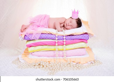 Newborn Baby Girl In A Crown Sleeping On The Bed Of Mattresses. Fairy Princess And The Pea