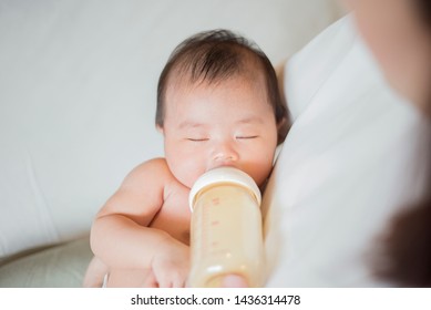Newborn baby girl is drinking milk by  her mother 