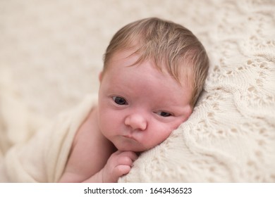 Newborn Baby Girl, Lying In A White Background With Her Eyes Wide Open.