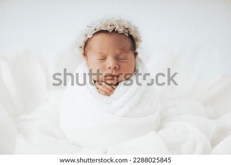 Newborn baby girl photographed in studio, on white background. Stylized and wrapped in paper flower. Fineart.