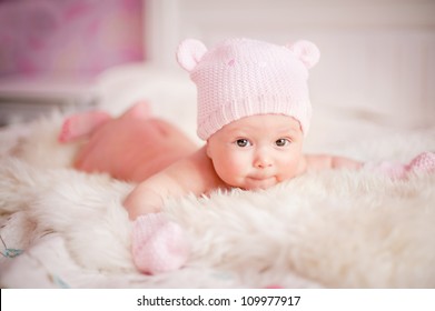 Newborn Baby Girl In Pink Knitted Bear Hat Lies At Fur