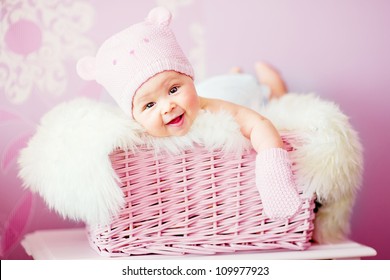 Newborn Baby Girl In Pink Knitted Bear Hat Lies At Basket