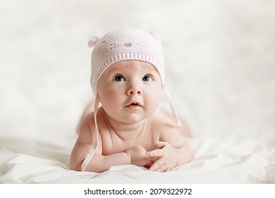 Newborn baby girl in pink knitted hat on a bed.  - Shutterstock ID 2079322972