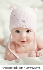 Newborn baby girl in pink knitted hat on a bed.  - Shutterstock ID 2079322975