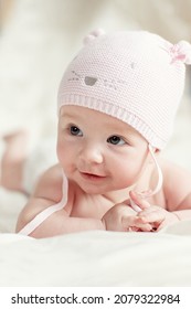 Newborn baby girl in pink knitted hat on a bed.  - Shutterstock ID 2079322984