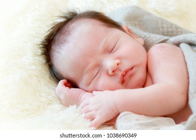 Newborn baby girl is sleeping on fur blanket