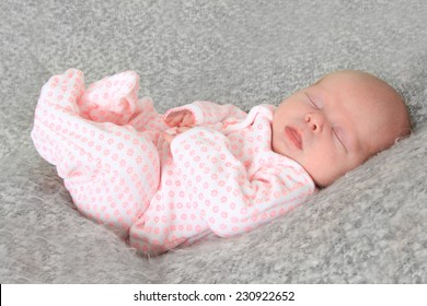 Newborn Baby Girl Wearing A Pink Sleeper. 