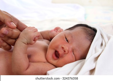 Newborn Baby Girl Wrapped In White Blanket Crying And Holding Her Mom's Hands